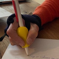 Hand met een aangepaste, verdikte pen die schrijft op gelinieerd papier